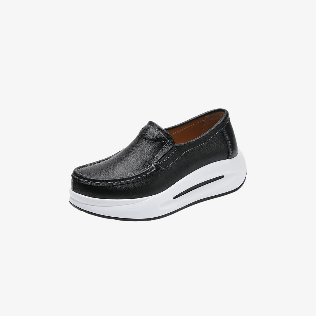 Women's black faux leather loafers with a thick white sole for a modern, comfortable look. Their minimalist design includes visible stitching and an easy fit, perfect for an elegant yet casual look.