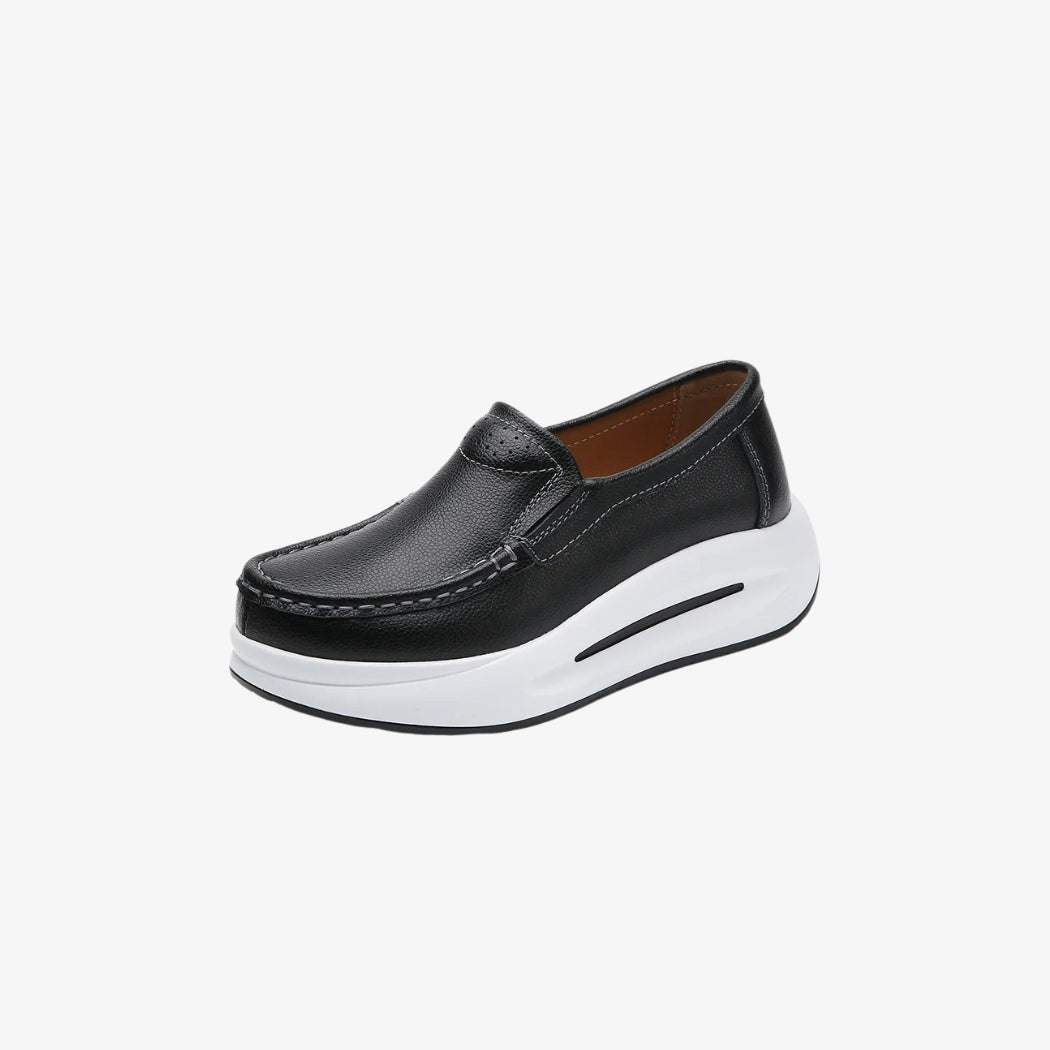 Women's black faux leather loafers with a thick white sole for a modern, comfortable look. Their minimalist design includes visible stitching and an easy fit, perfect for an elegant yet casual look.