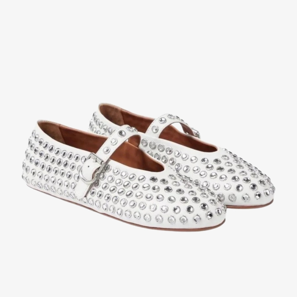 White loafer flats with crystals and a Mary Jane strap, on a gray background