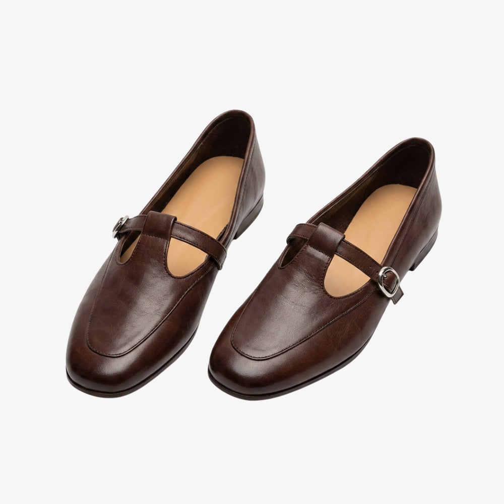 Vintage style loafer flats with a T-shaped strap, in brown, on a gray background