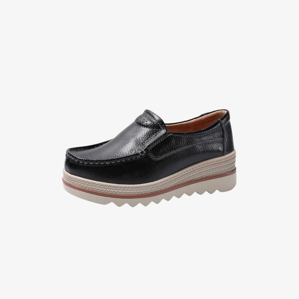 Women's wedge loafers in black leather-look material, with an elegant, timeless design. These shoes have a thick beige sole with braided details and a treaded base for better grip. The interior is designed for optimal comfort all day long.