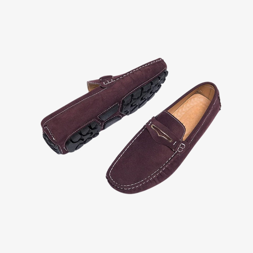 Comfortable burgundy suede loafers for men. These stylish shoes feature white contrast stitching, a discreet metal buckle on the vamp and a black lugged sole for better grip. The padded interior ensures optimal everyday comfort.