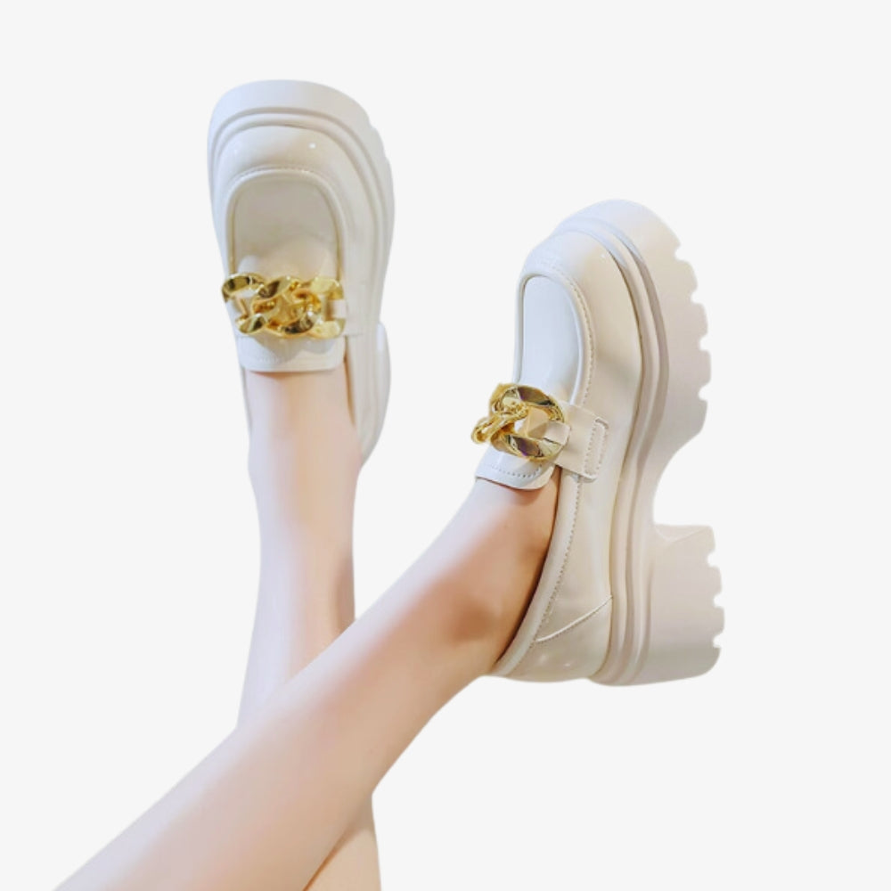 White loafer with chunky black sole and gold buckles on a white background
