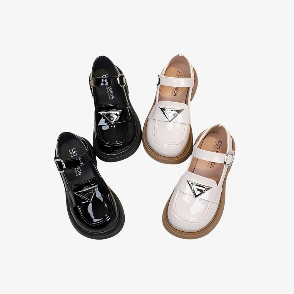 2 pairs of shiny black and white loafers with silver details, on a gray background.