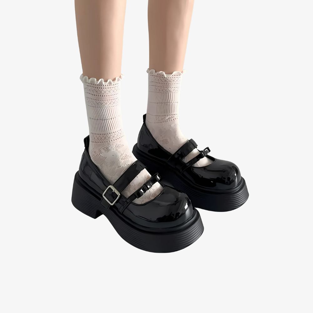 Woman's legs wearing black platform loafers with two straps and white knee socks.