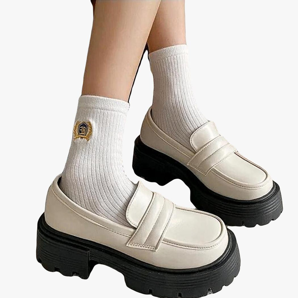 A woman's feet in white synthetic leather wedge loafers