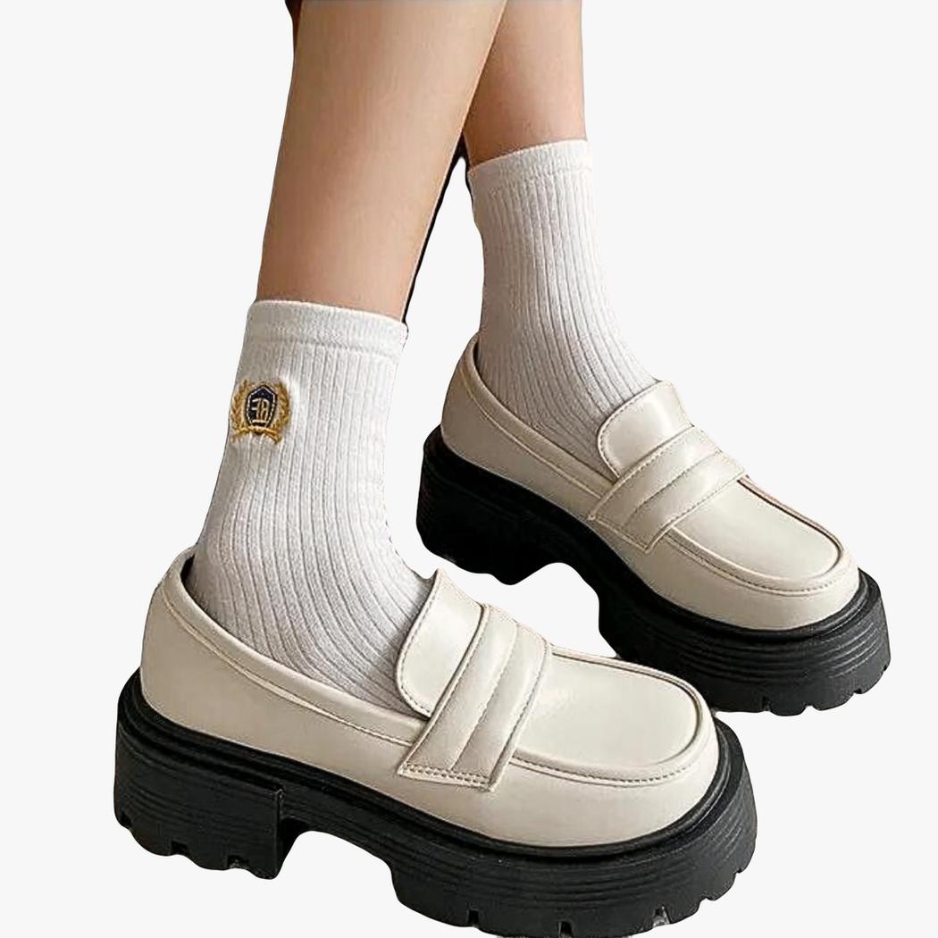 A woman's feet in white synthetic leather wedge loafers