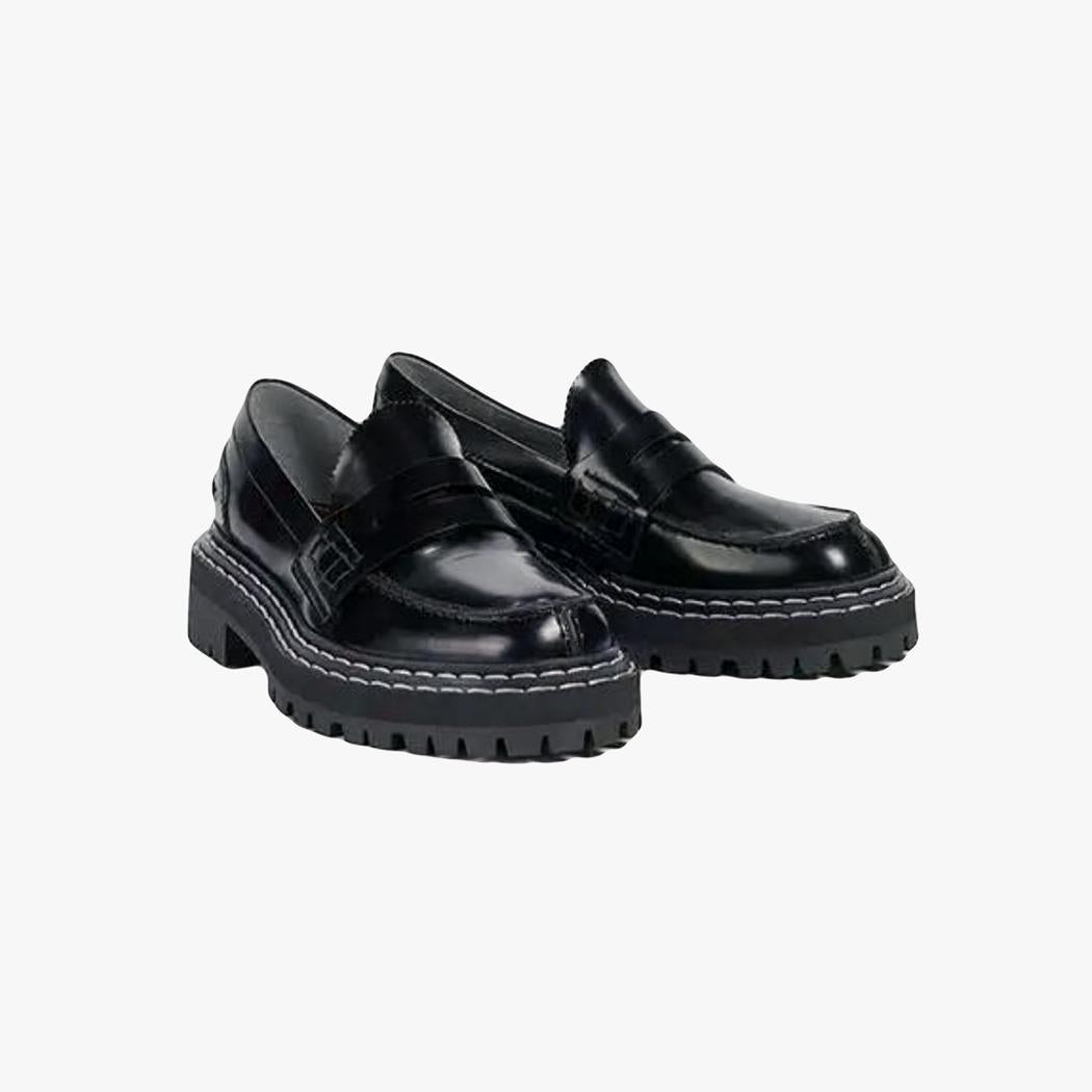 A pair of women's black faux leather loafers with chunky soles on a light grey background