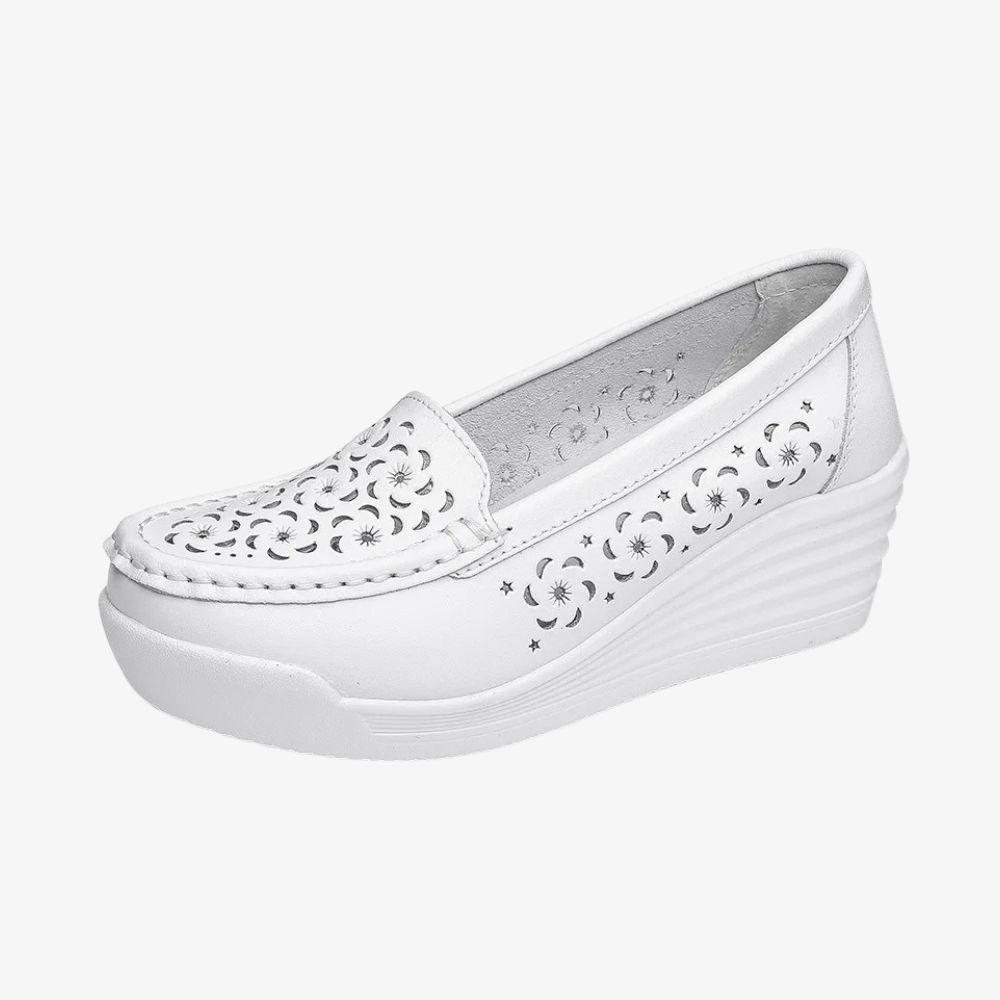 A white loafer in profile, with a wedge sole and holes on the front and sides.