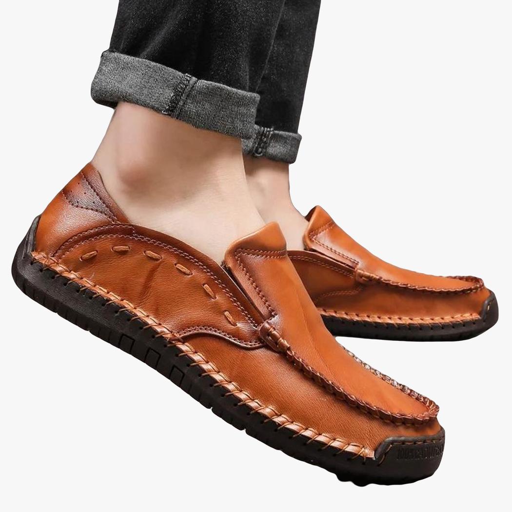 A man's feet wearing soft faux leather loafers in camel