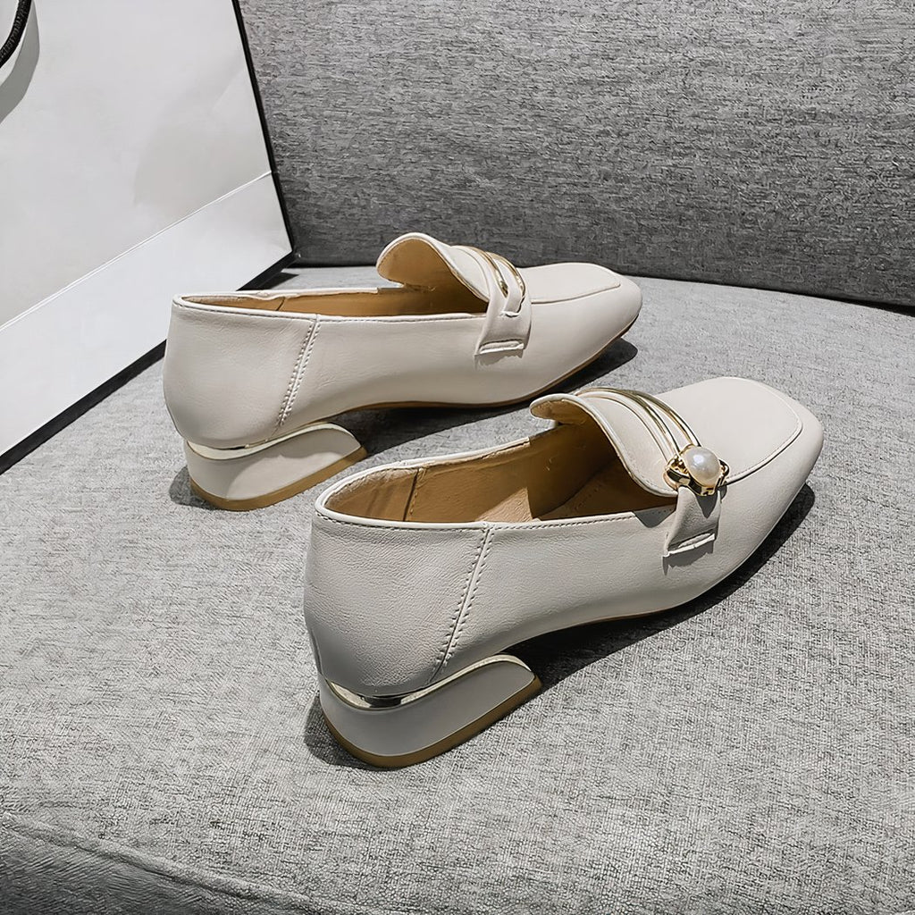 white faux leather loafer with a small heel on a grey sofa