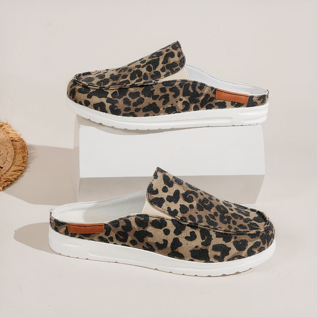 Shown in profile, pair of leopard print canvas round sport loafers with thick white soles. One shoe on a white display and one underneath on a white floor