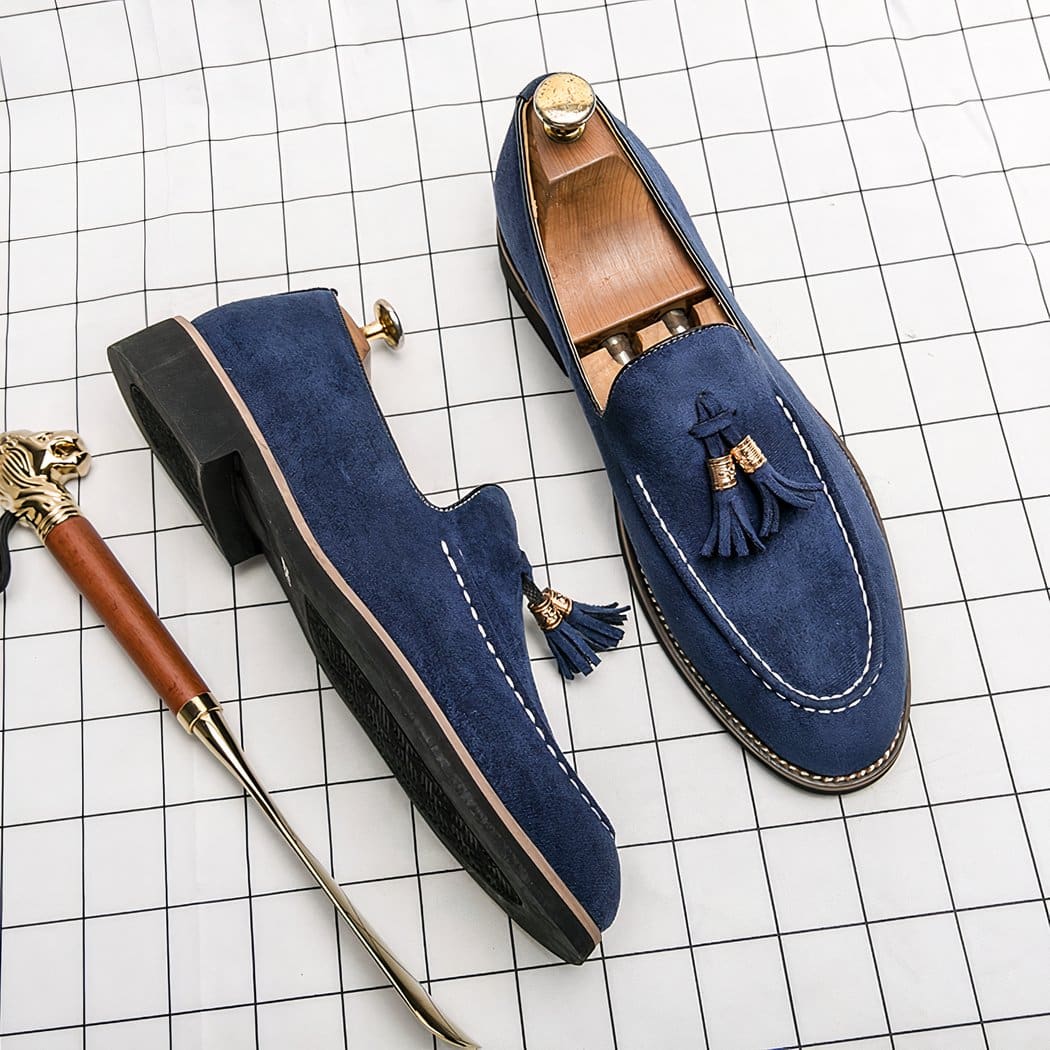 Blue loafers with side shoe, all set on a white checkered surface.