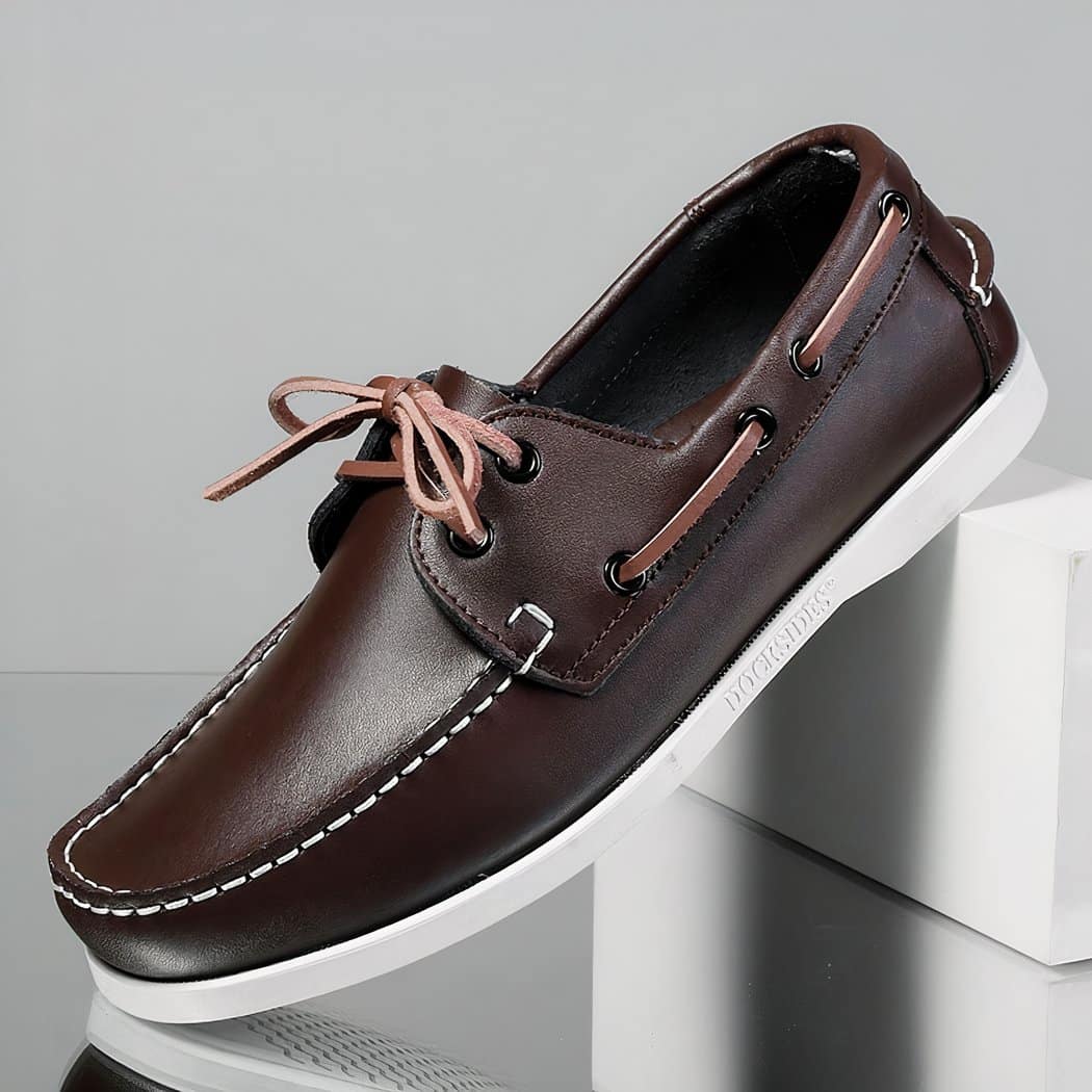 Photo of a black boat loafer on a white piece of furniture with a grey background