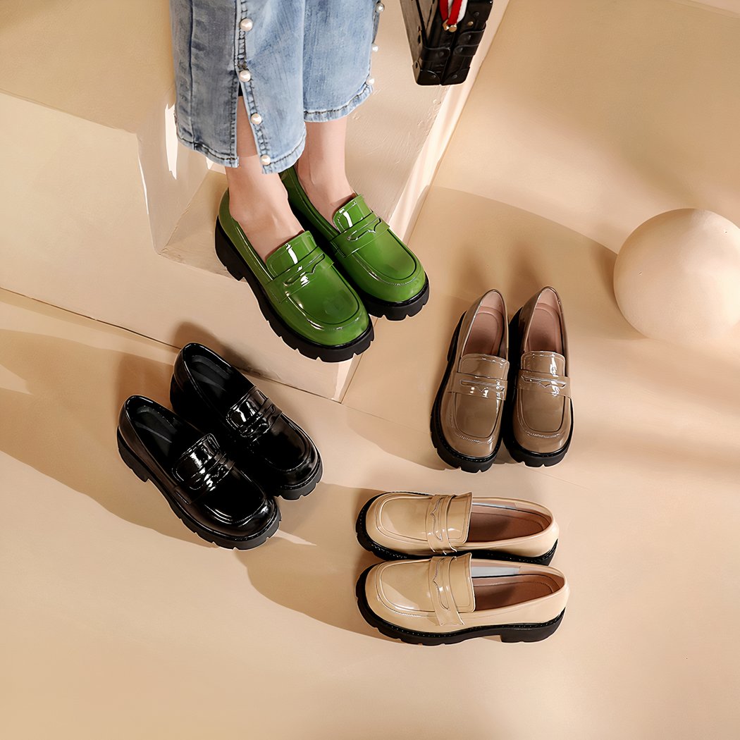 Four pairs of patent leather loafers with thick soles, simple on a beige floor, the green pair is on the feet of a woman wearing light blue jeans, the other pairs are beige, brown or black.