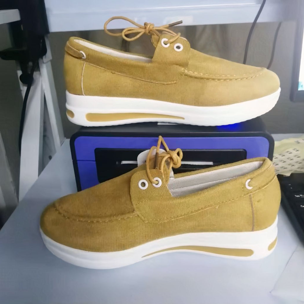 Yellow loafers with white heels in front of a box.