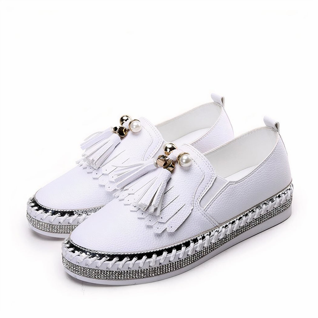 Pair of white loafers with rhinestones and bangs on the front, on a white background