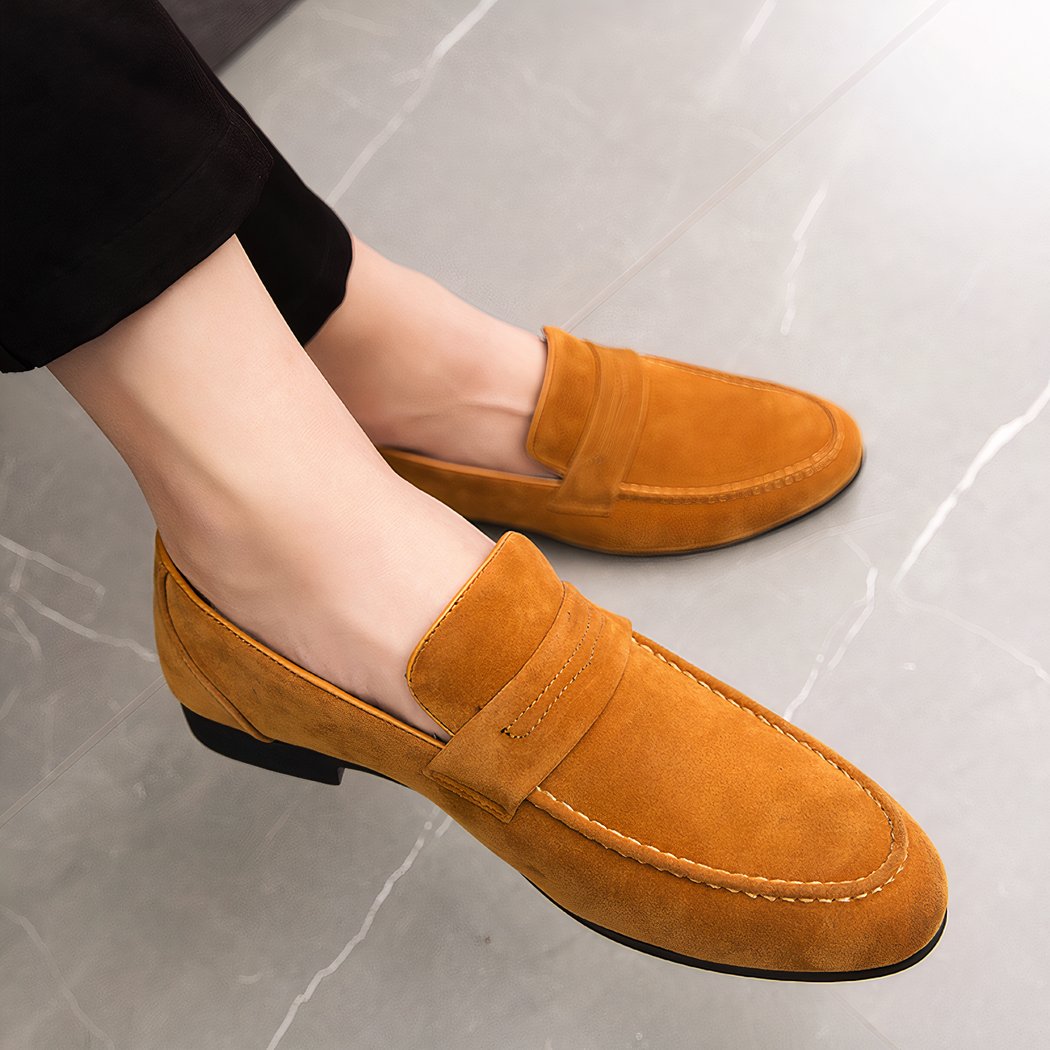 brown loafers worn by a cross-legged man with black pants