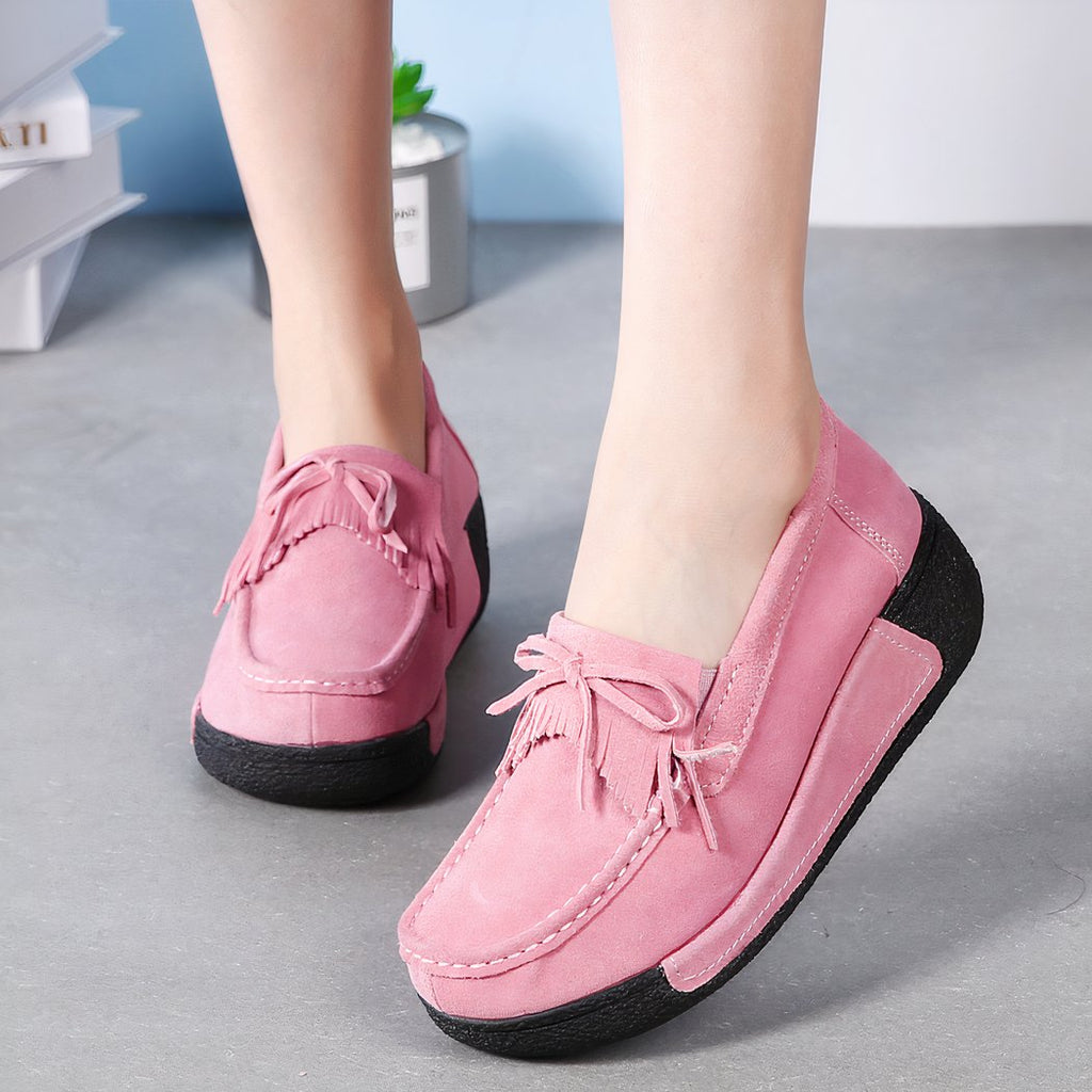 Feet with pink loafers with fringe and bow on front