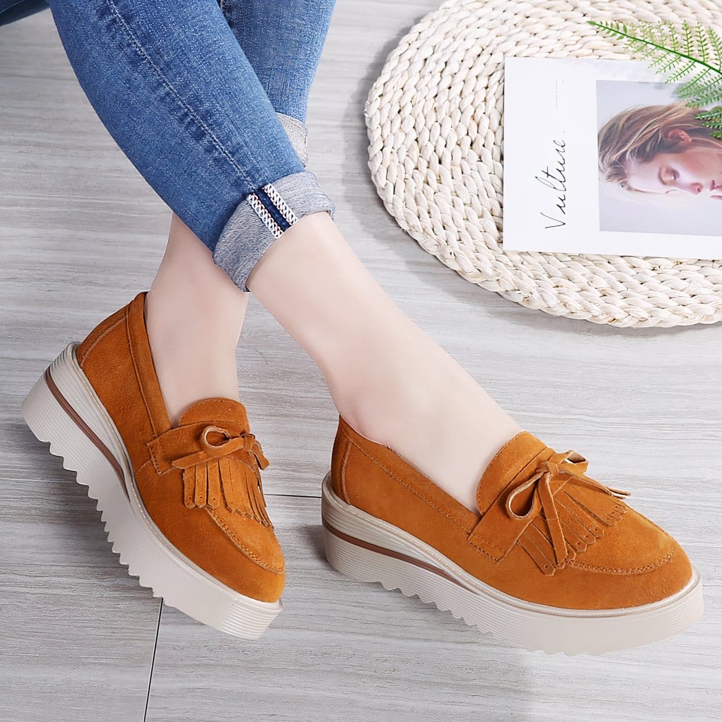 orange tassel wedge loafer worn by a woman