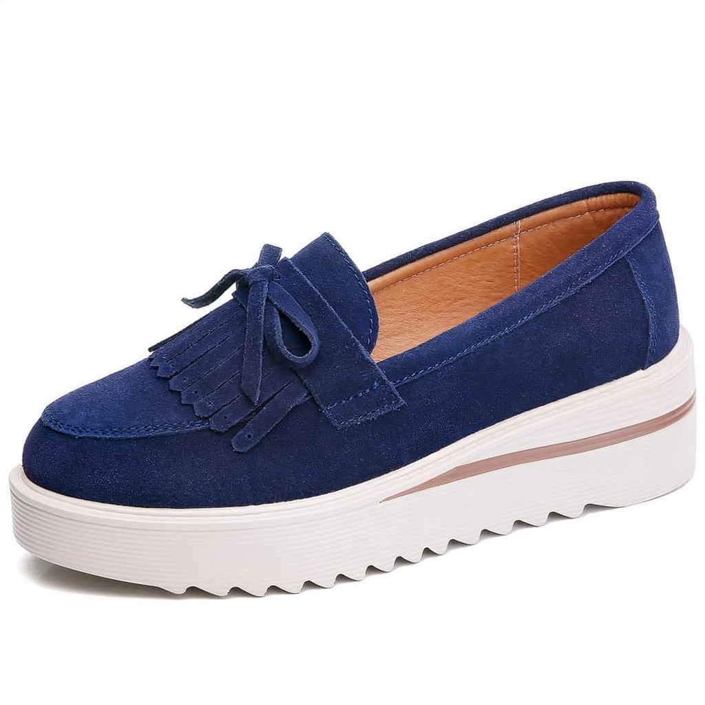 blue suede wedge loafer with white sole under a white background