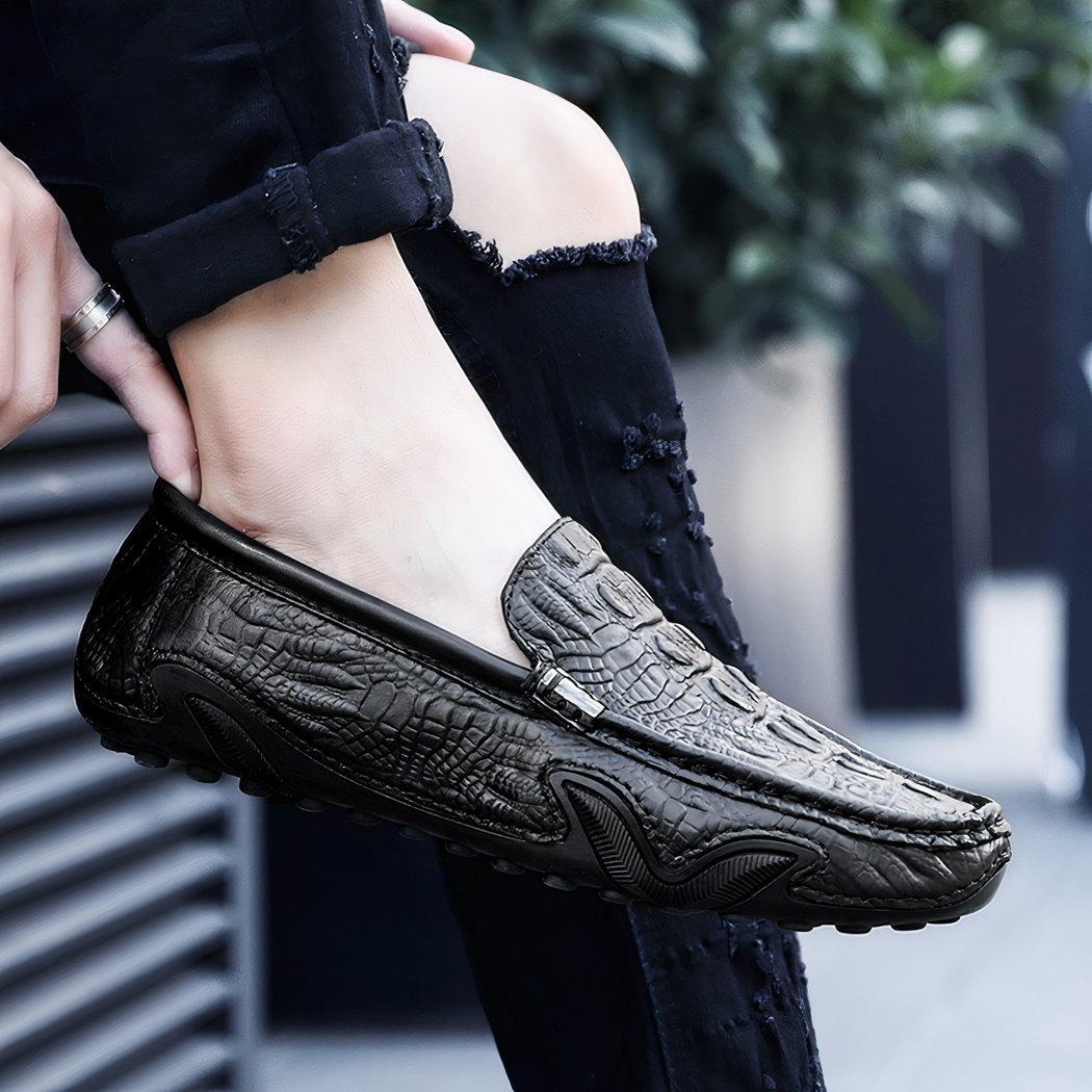 Photo of a black leather loafer worn by a woman in black pants on a street