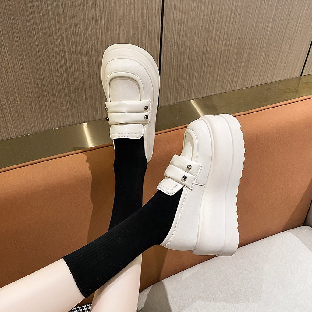 Thick white loafers worn by a person whose calves can only be seen.