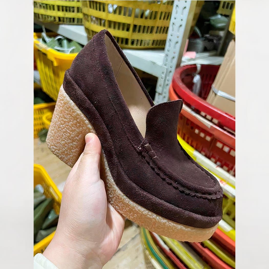 suede loafer with brown heel for women held in a woman's hand