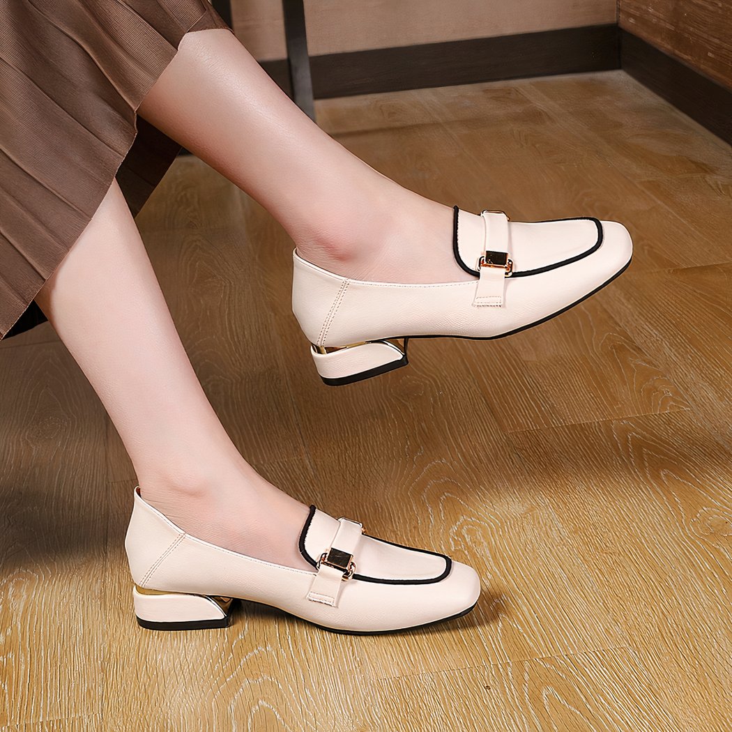 Woman in brown dress sitting in white loafers with black stitching on the foot