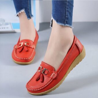 Photo of a pair of red moccasins worn by a woman in jeans, on a gray floor with a white wall