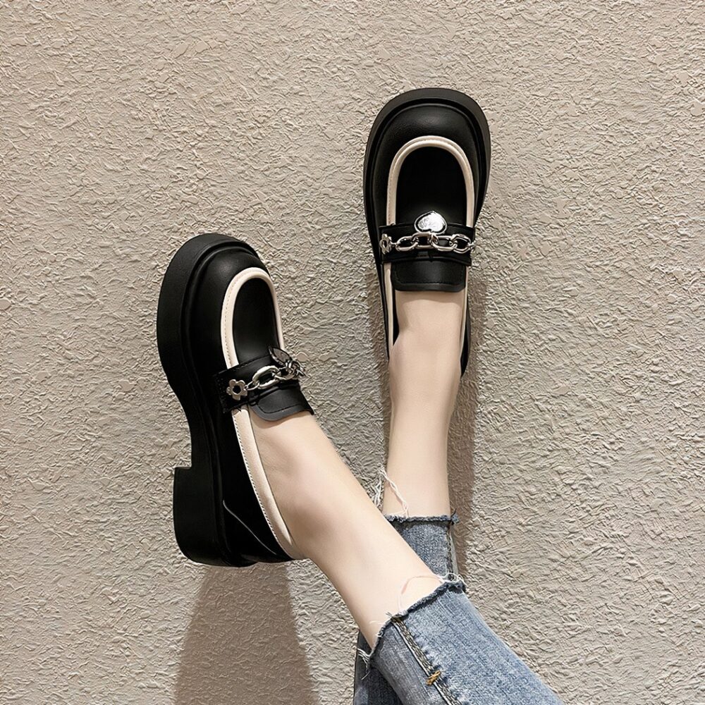 Photo of a pair of black platform loafers worn by a woman in jeans on a beige floor