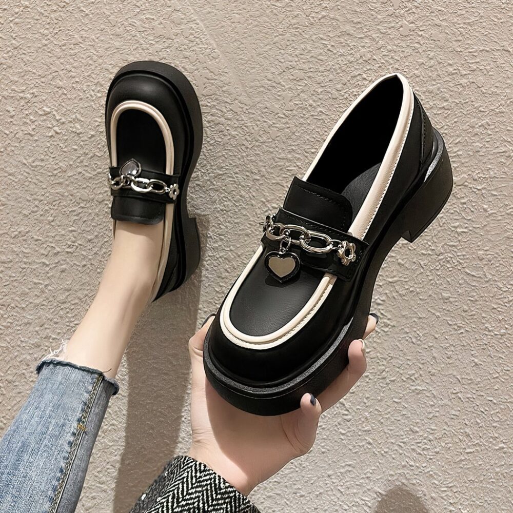 Photo of a pair of black platform loafers worn by a woman in jeans on a beige floor