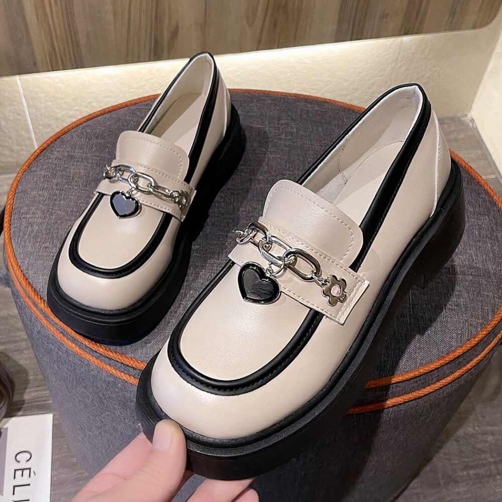 Photo of a pair of white platform loafers on a gray stool