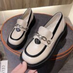 Photo of a pair of white platform loafers on a gray stool