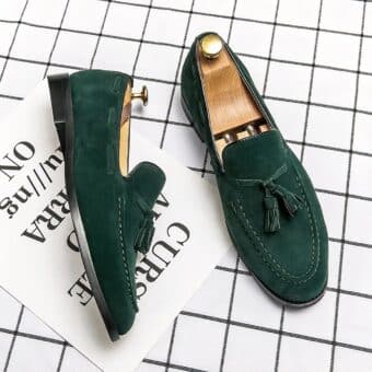 Pair of green moccasins with tassels on a white checkered surface