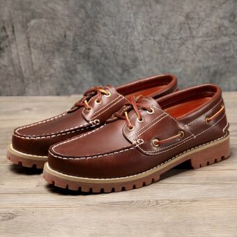 Photo of a pair of brown boat moccasins on a parquet floor with a gray wall behind