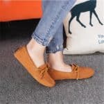 Brown moccasins worn by a woman whose calves can only be seen.