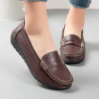 Brown loafers worn by a woman with only her ankles showing.