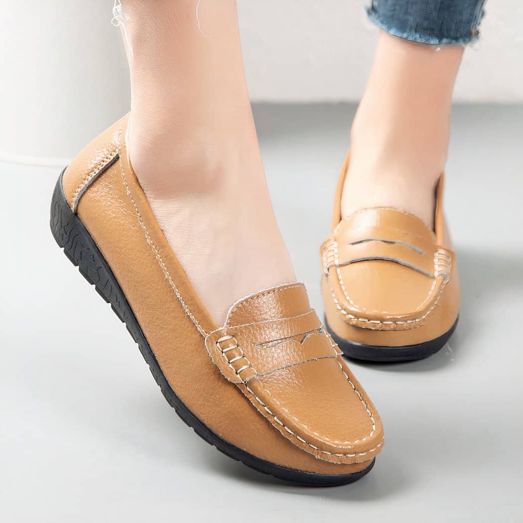 Photo of a pair of brown moccasins worn by a woman on gray ground