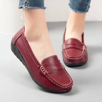 Photo of a pair of red moccasins worn by a woman on gray ground