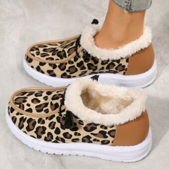 Leopard-print boat moccasins with white sole and exposed fur inside. The pair is in profile on a gray ground with a woman's foot inside