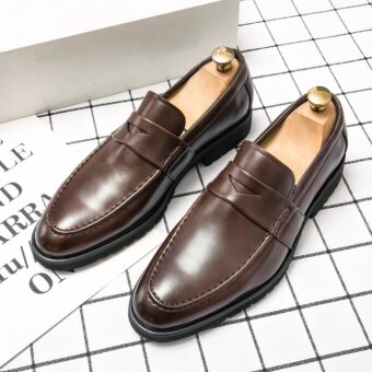 Brown leather moccasin on a checkered floor with a leaf and writing next to it