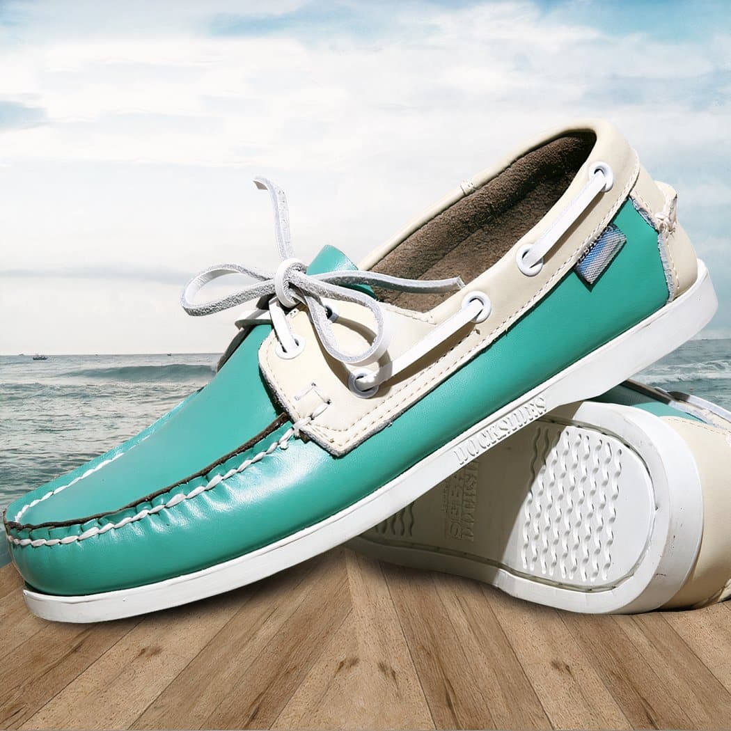 Photo of a pair of blue boat moccasins on a parquet floor and a marine background with a cloudy blue sky