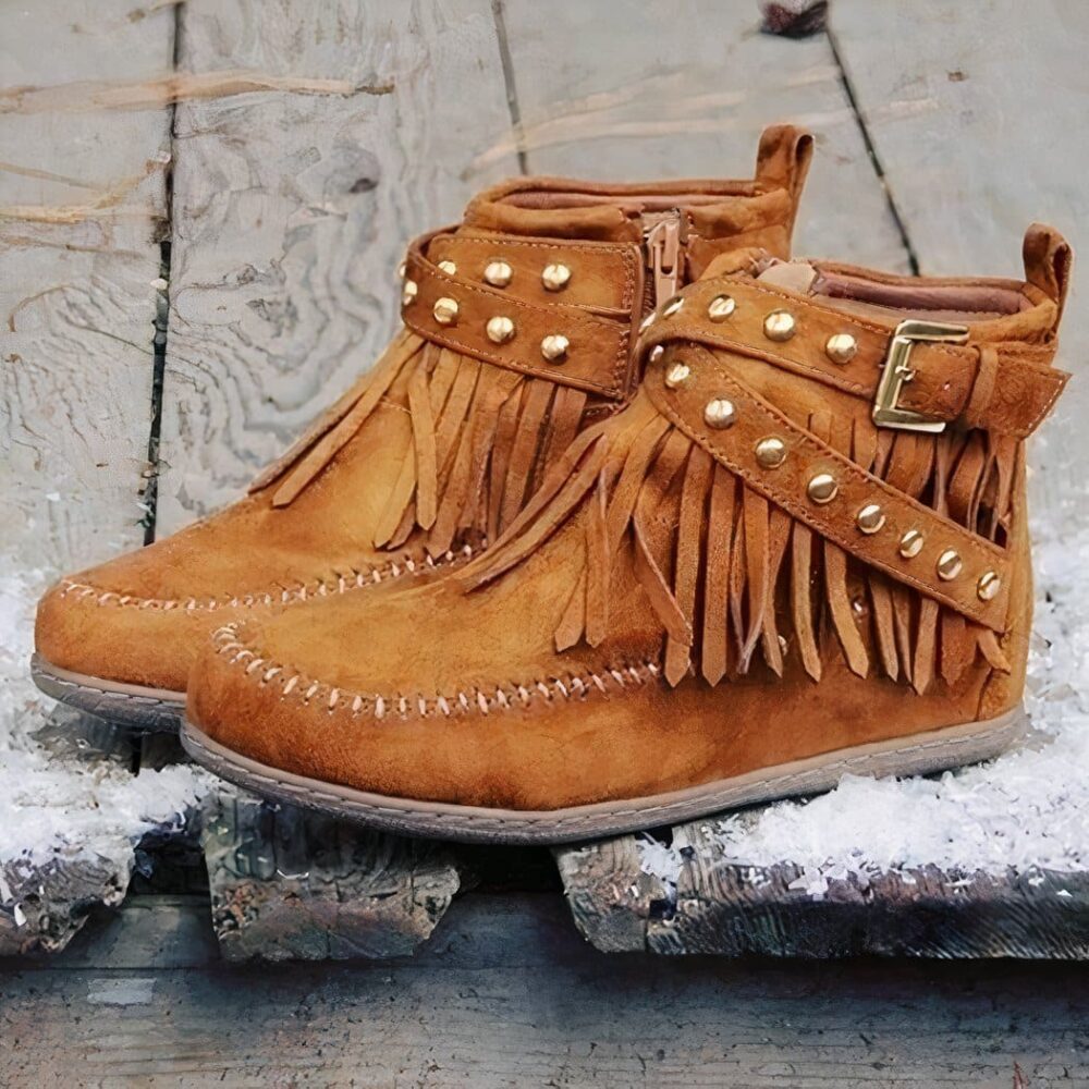 Indian moccasins with bangs and buckles in camel suede on wooden boards