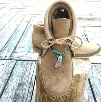 Beige suede lace-up Indian moccasin with ethnic jewelry around the ankle