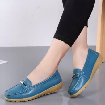 Photo of a pair of blue platform loafers worn by a woman in black pants on a gray floor and white wall