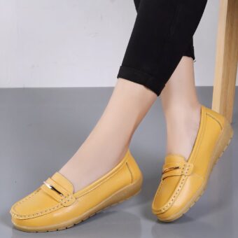 Photo of a pair of yellow platform loafers worn by a woman in black pants on a gray floor and white wall