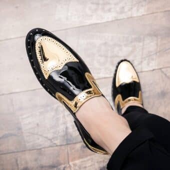 Crossed feet in black and gold patent loafers on a parquet floor