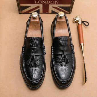 Black loafers with tassel on top on the floor with a shoe next to it