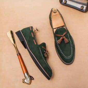 Pair of green moccasins with tassels and a shoehorn on the side